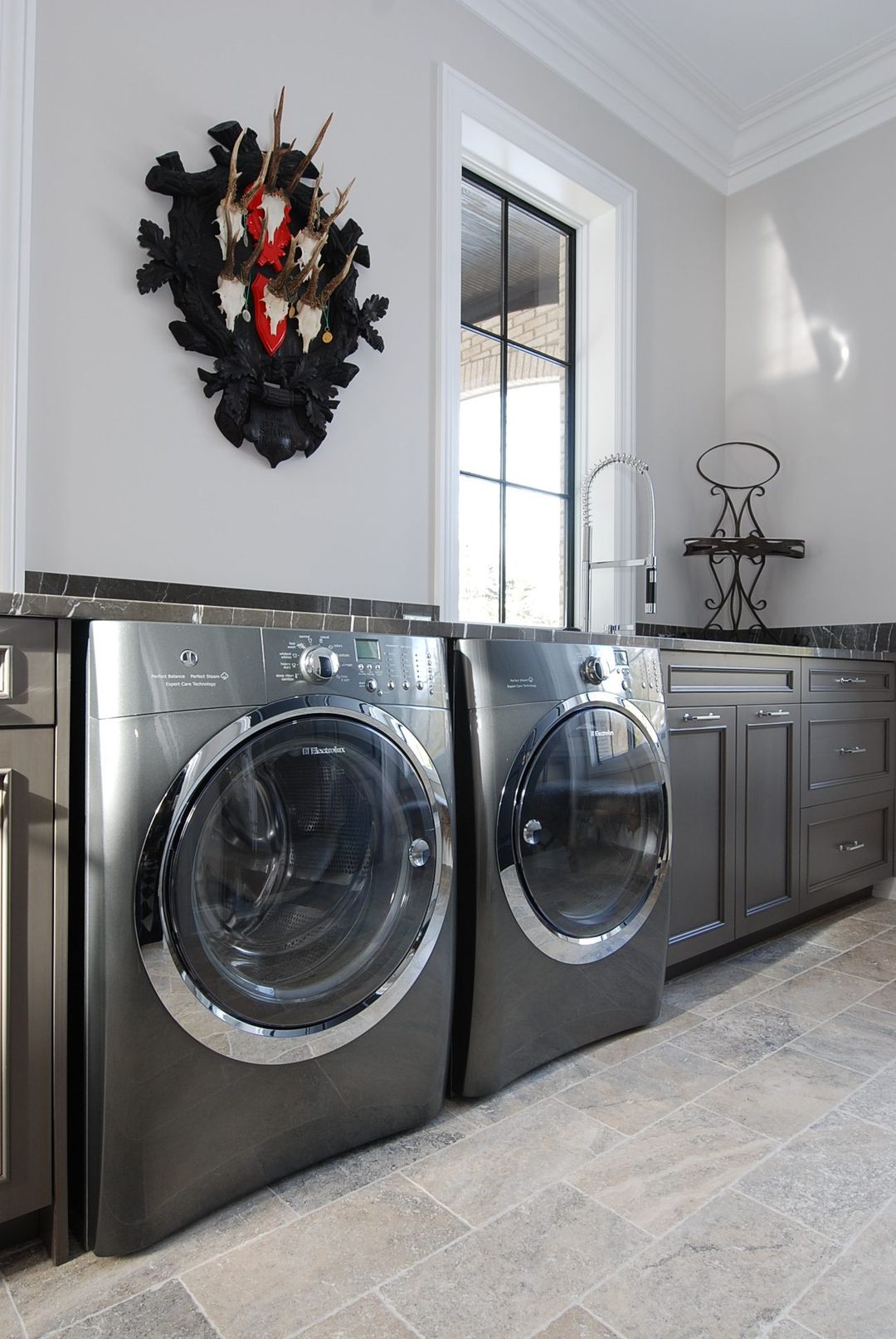 Barrington luxury laundry room with front loader washer dryer, dark cabinetry, marble countertop, and stone tile - Kelly Thayer Design