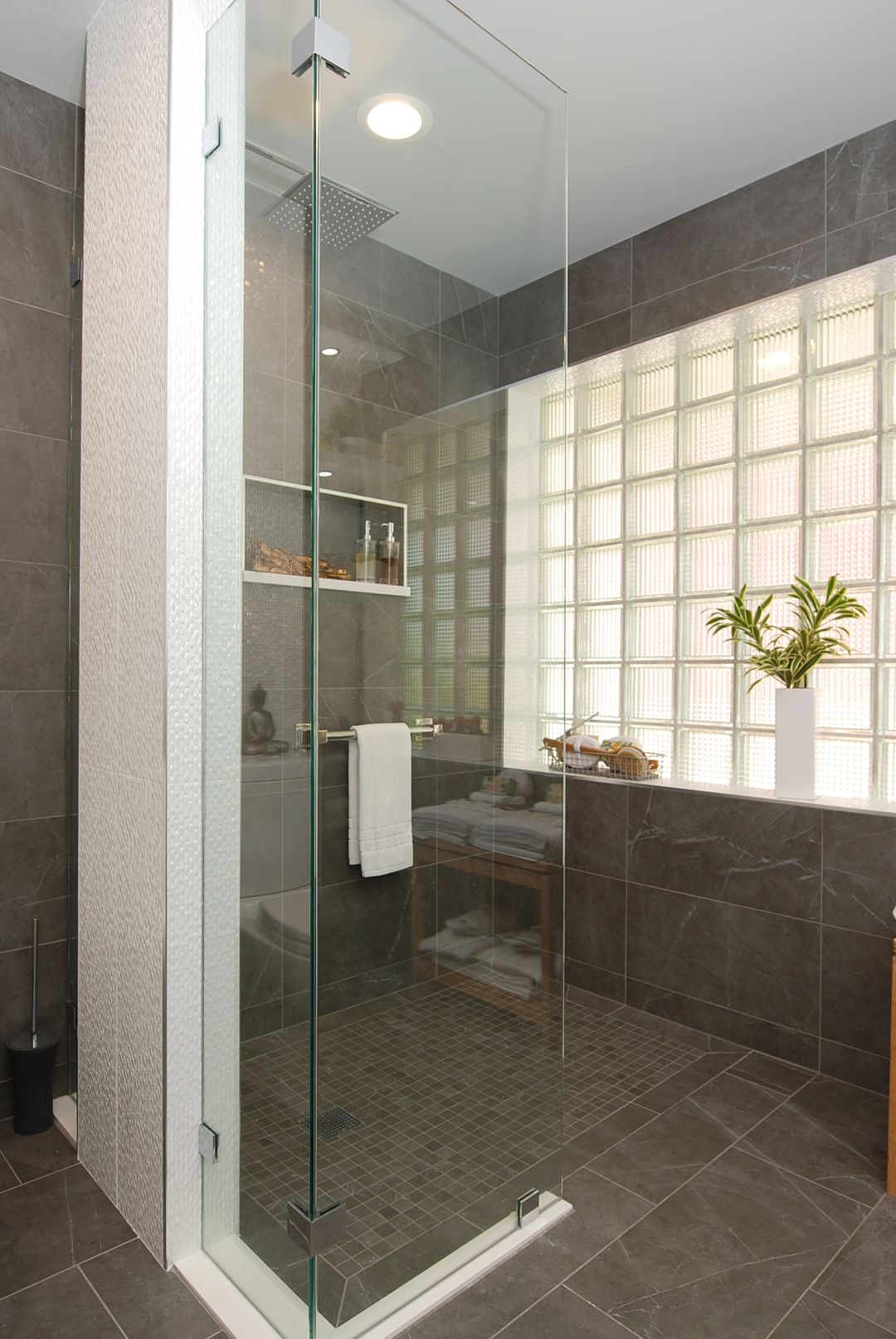 North Shore open curbless shower with gray stone tile, glass block window, and ceiling flush rain head – Kelly Thayer Design