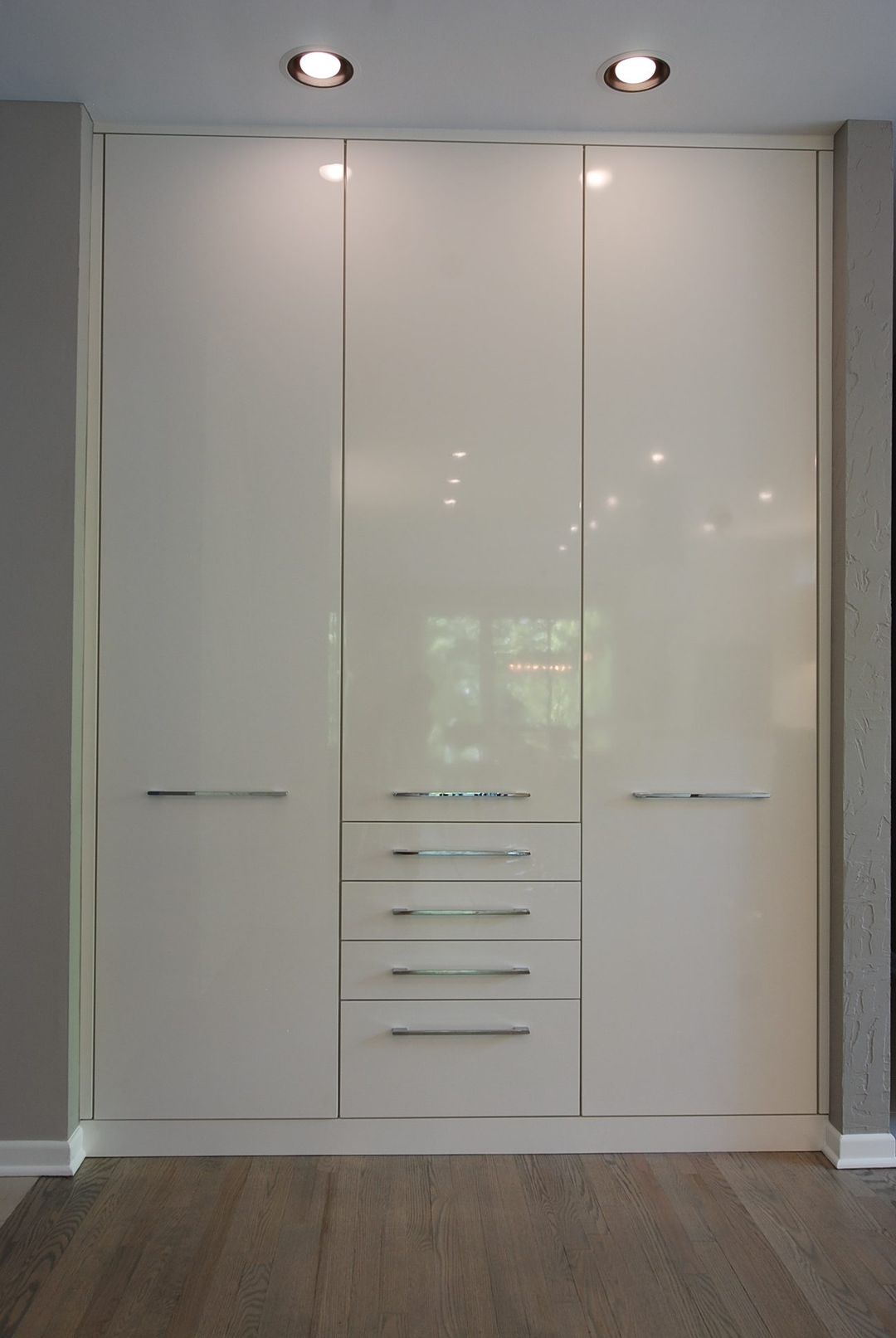 Riverwoods custom built-in wardrobe with high-gloss cream cabinet doors and center drawer stack - Kelly Thayer Design