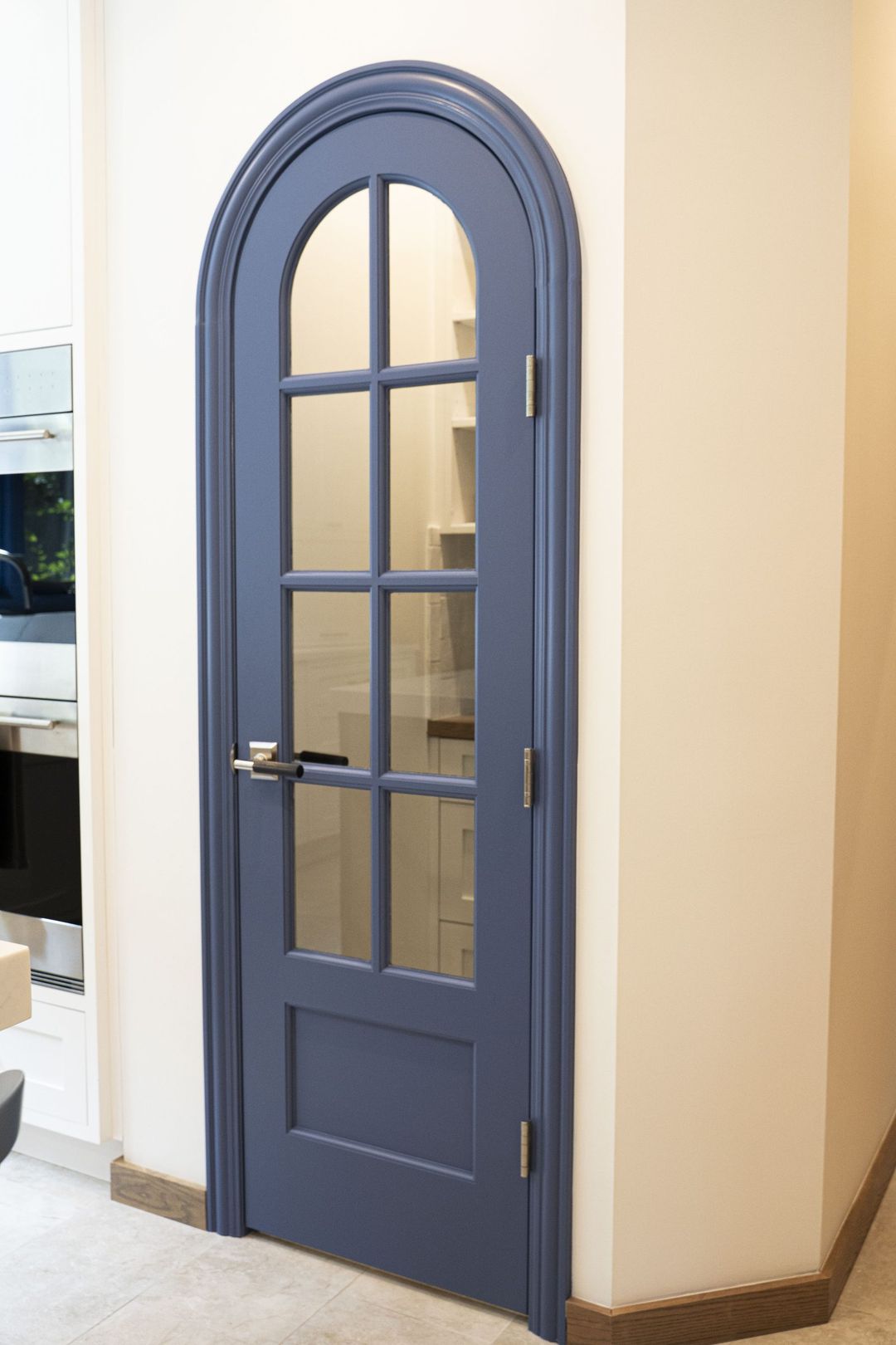 Winnetka walk-in pantry with custom arched blue glass panel door and white kitchen cabinetry - Kelly Thayer Design