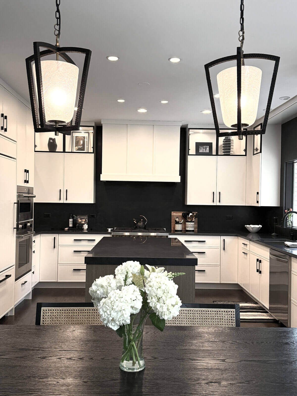 Northbrook Kitchen Remodel - Hidden Storage | Kelly Thayer Design Black metal lantern pendants over dining table facing black and white Kildeer kitchen remodel