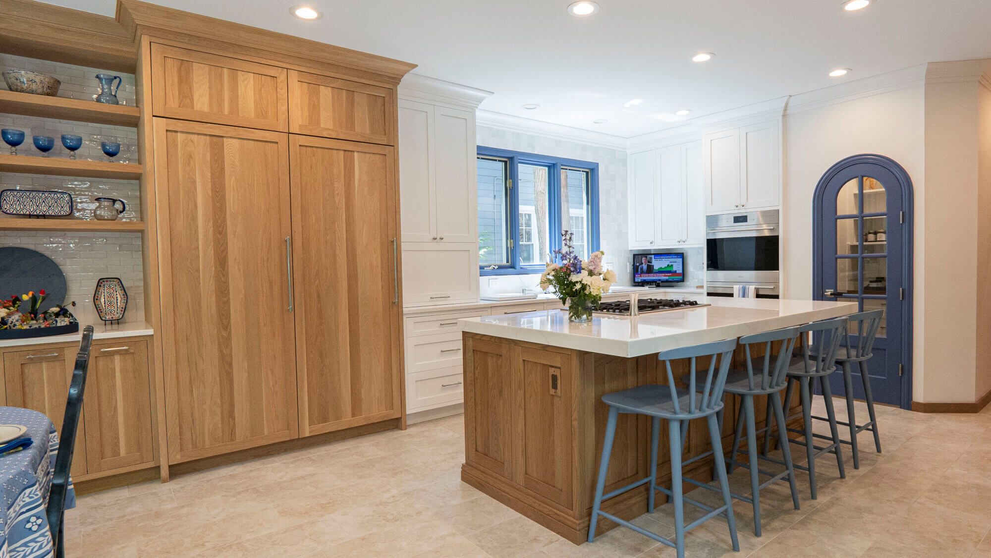 Two-toned Winnetka kitchen remodel with white oak cabinets, quartz island, and blue arched pantry door