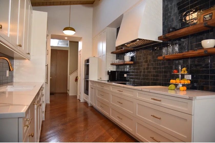Highland Park ravine home kitchen with custom white hood, black subway tile, and reclaimed wood floating shelves by Kelly Thayer Design