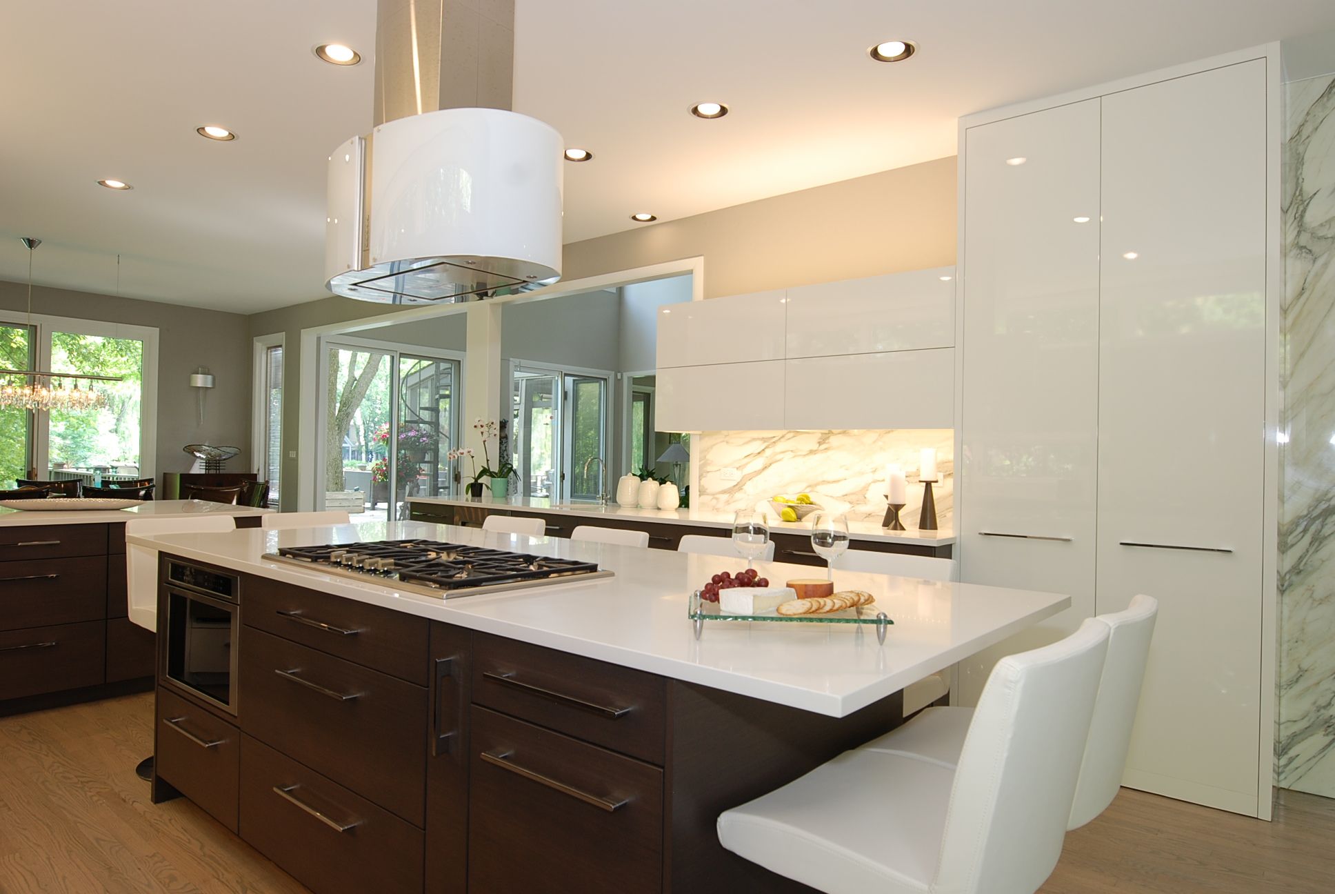 Contemporary kitchen with Calacatta marble backsplash, high-gloss white cabinets, and dark walnut wood island by Kelly Thayer